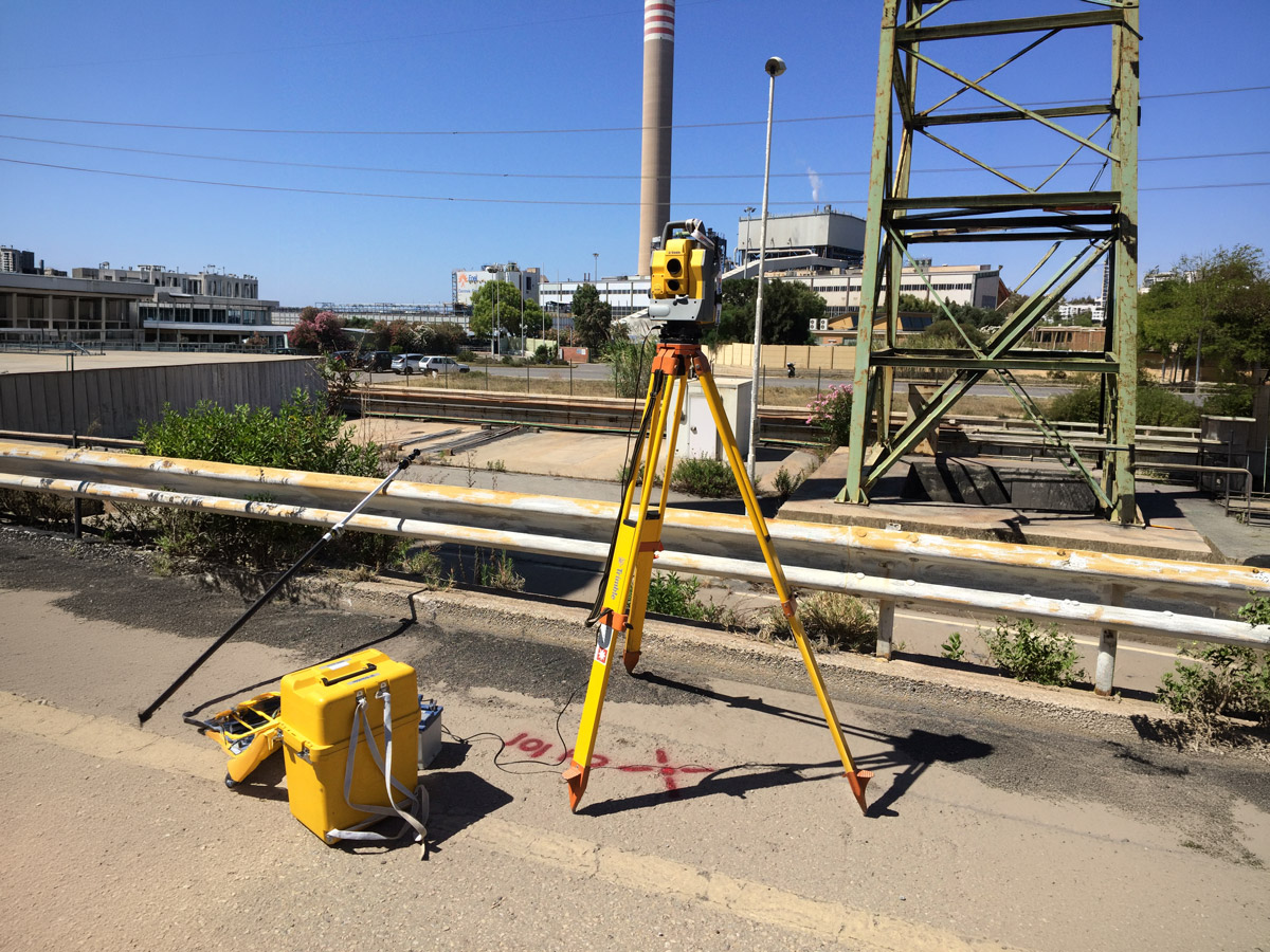 Stazione totale Trimble su treppiede durante un rilievo topografico in un impianto industriale